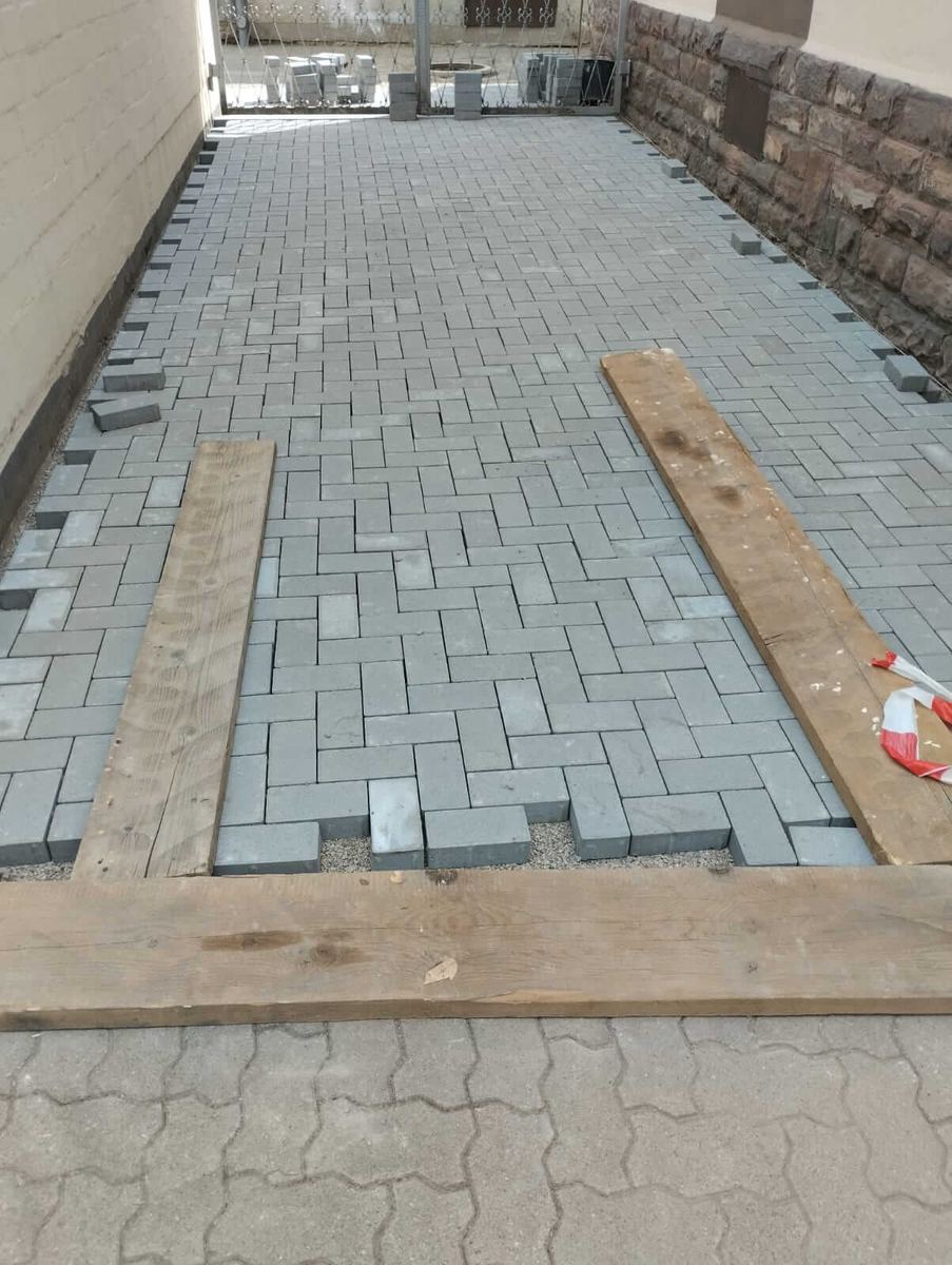 Hofeinfahrt im Verband zwischen Hauswand und Natursteinmauer, die Randsteine sind gesetzt